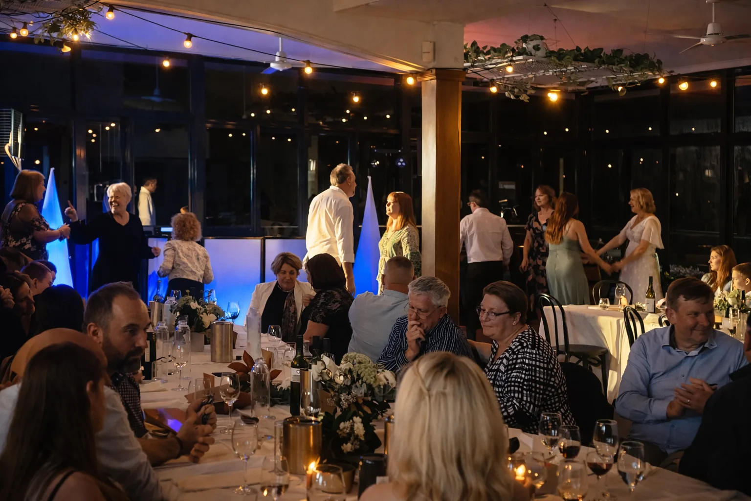 Wedding reception with guests dining and dancing under festoon lights